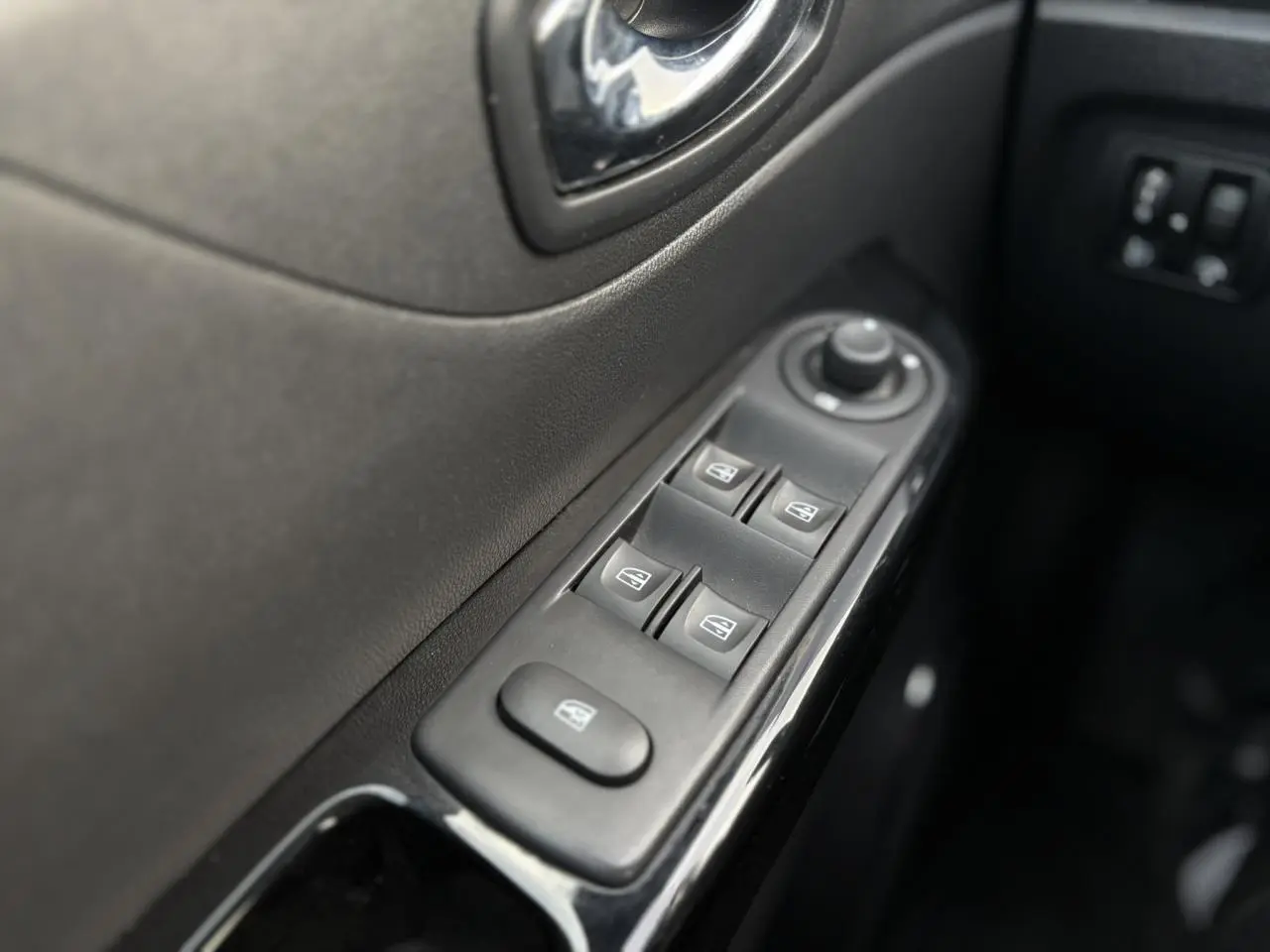 Gros plan sur les commandes des vitres électriques côté conducteur du Renault Captur gris Cassiopée, intérieur noir.