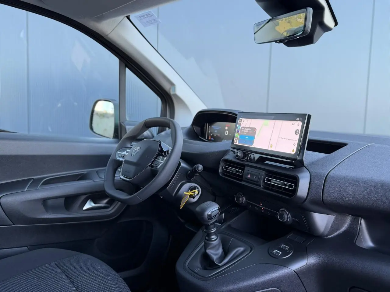 Vue intérieure côté conducteur du Peugeot Partner blanc Icy, avec tableau de bord moderne et écran tactile central.