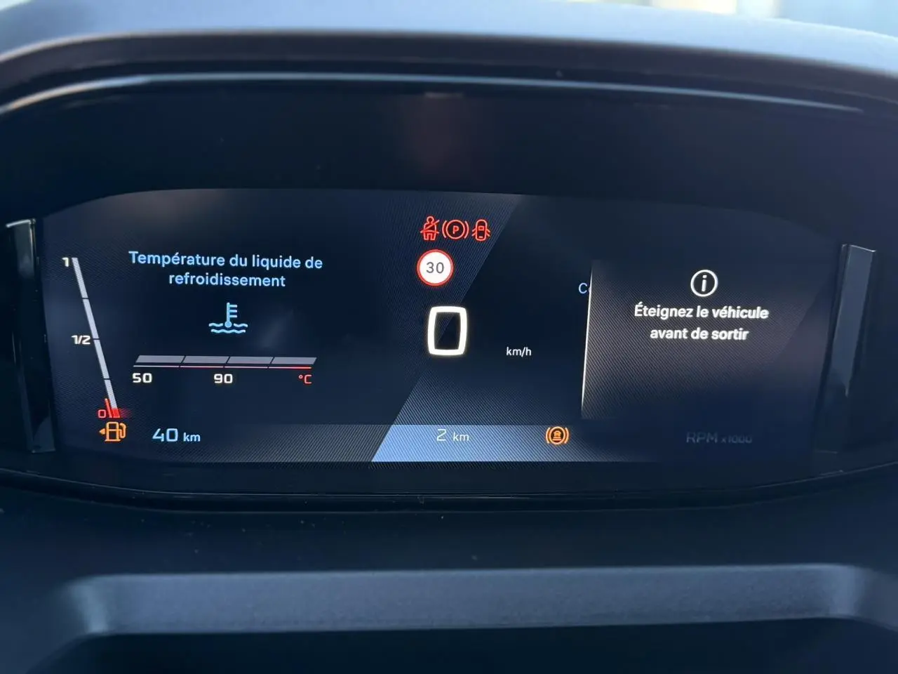 Tableau de bord numérique 10 pouces du Peugeot Partner 2026 affichant la température liquide refroidissement et alertes.