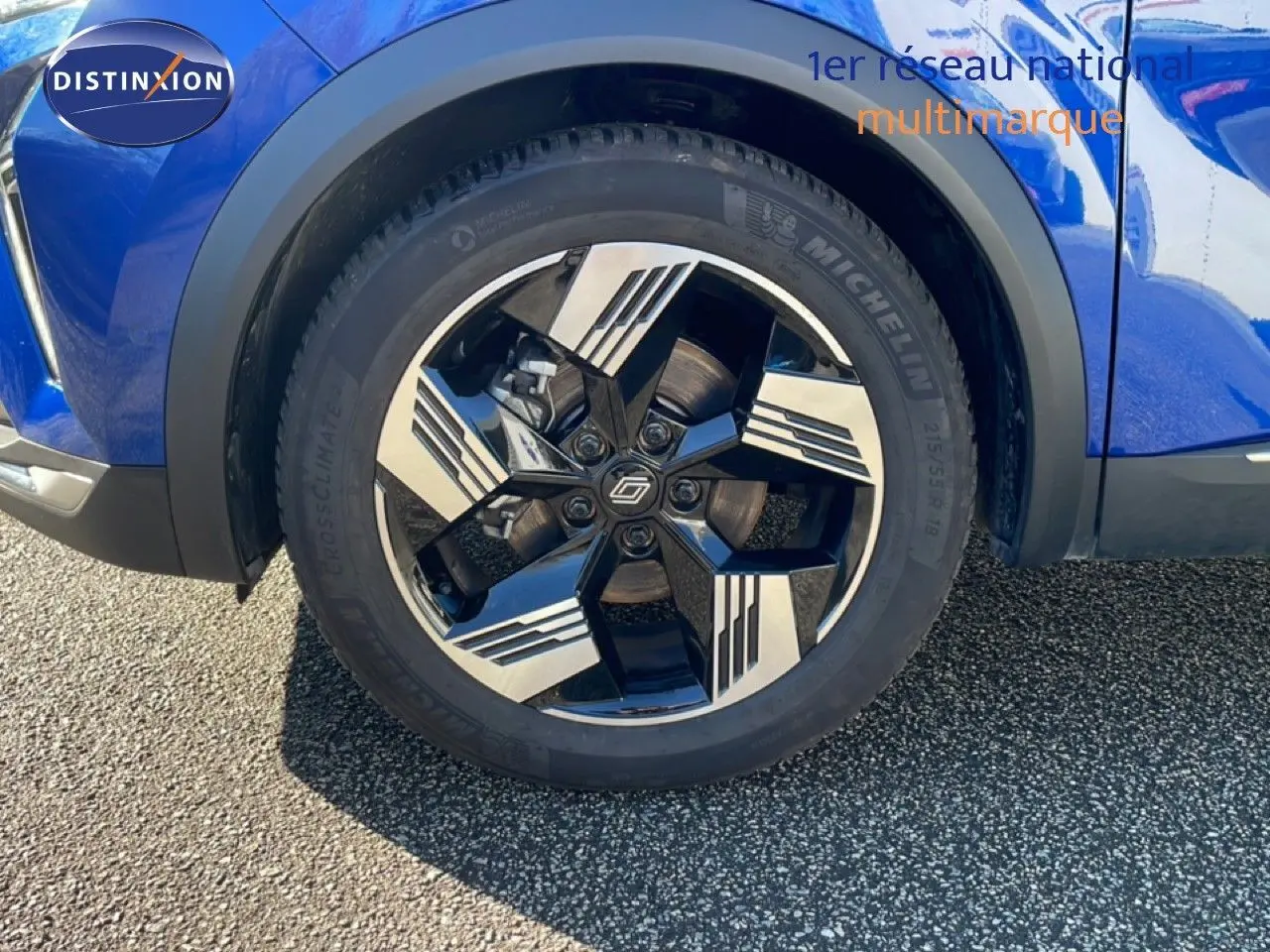 Gros plan sur la roue avant droite d'une Renault Symbioz bleu iron metal avec jante alliage bicolore distinctive.