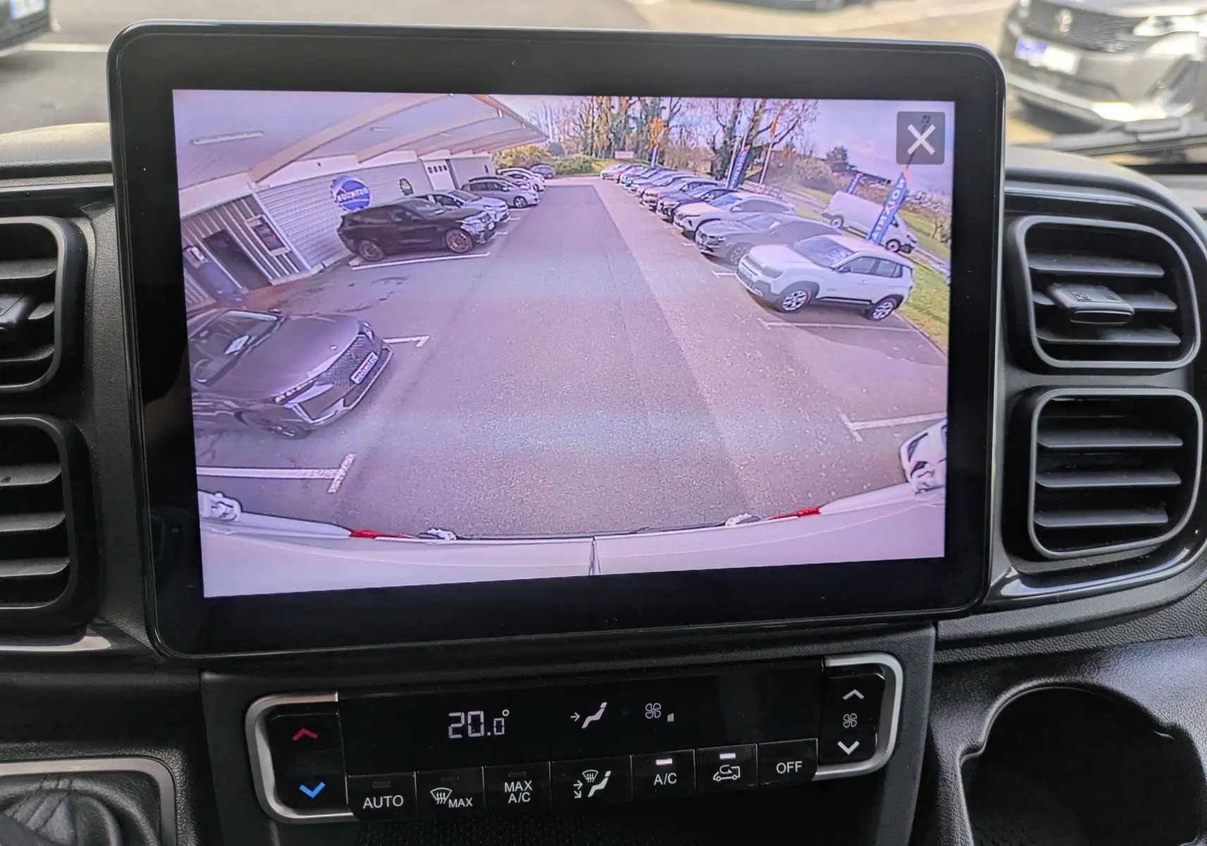 Écran de caméra de recul dans un Peugeot Boxer blanc montrant un parking avec plusieurs voitures vues de l'arrière.