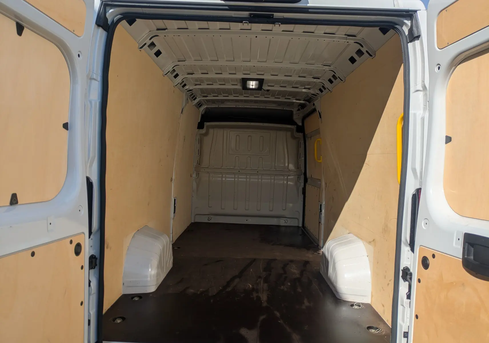 Vue intérieure arrière du Peugeot Boxer Fourgon blanc 2025, montrant l'espace de chargement vide avec parois en bois.