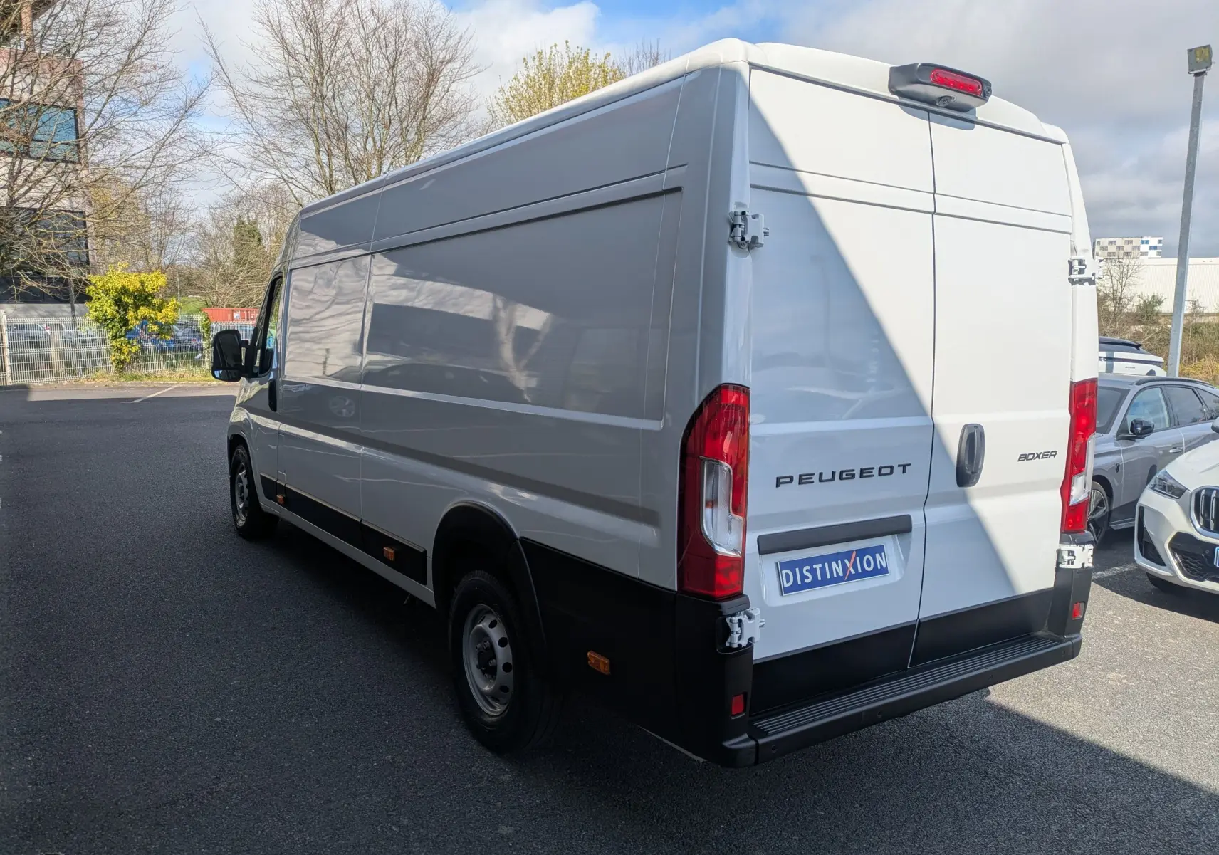 Vue 3/4 arrière droite d’un Peugeot Boxer Fourgon blanc, avec portes arrière fermées et jantes acier noires.