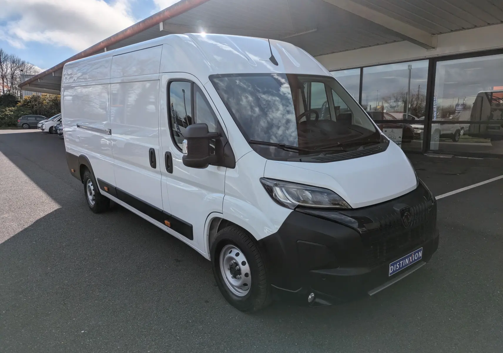 Vue 3/4 avant droit d’un Peugeot Boxer Fourgon blanc 2025 avec portes latérales coulissantes et jantes acier 16 pouces.