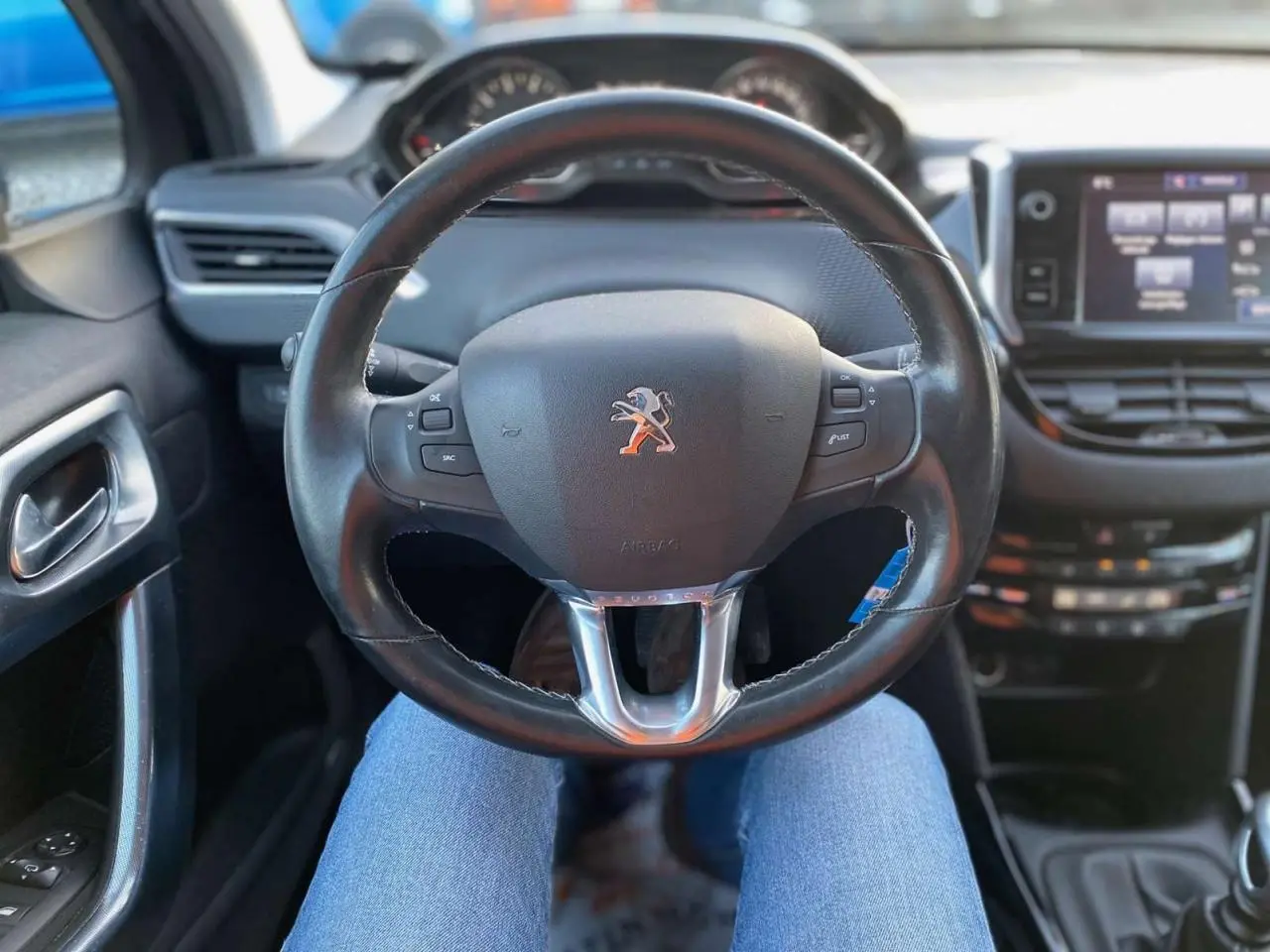 Vue intérieure centrée sur le volant cuir noir du Peugeot 2008 avec tableau de bord et écran tactile visibles.