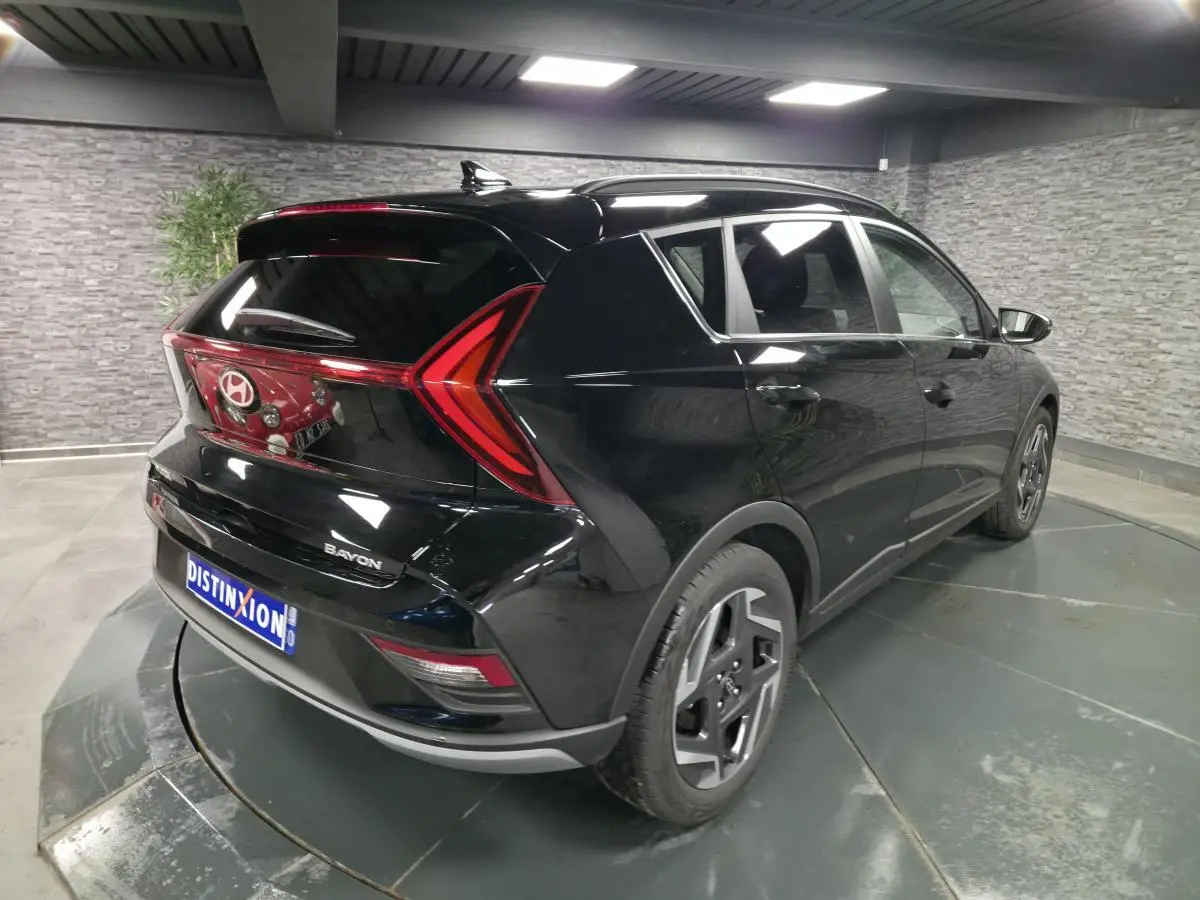 Vue 3/4 arrière droite d'une Hyundai Bayon noire 2025 avec feux arrière LED en forme de flèche et jantes alliage 17 pouces.