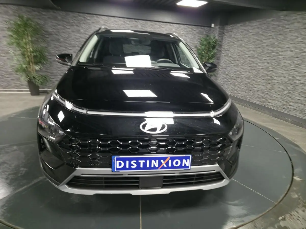 Vue avant d'une Hyundai Bayon 2025 noire avec calandre noire laquée et plaque Distinxion en intérieur showroom.