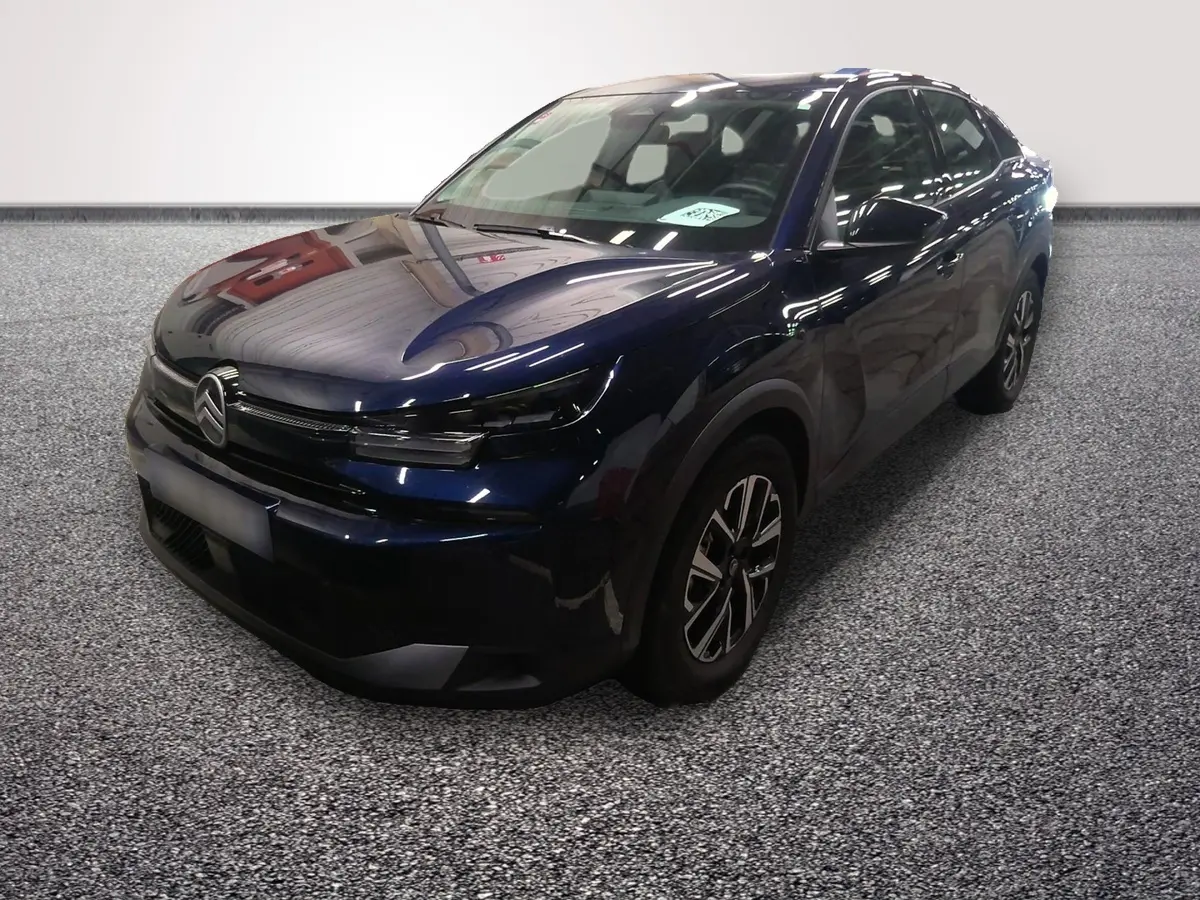Citroën C4 hybride bleu en 3/4 avant droit, avec calandre noire et phares LED fins, sur sol gris texturé.