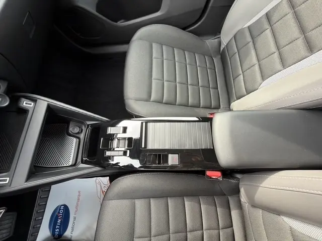Vue intérieure centrée sur la console centrale et sièges avant gris du Citroën C4 Hybride 2025.