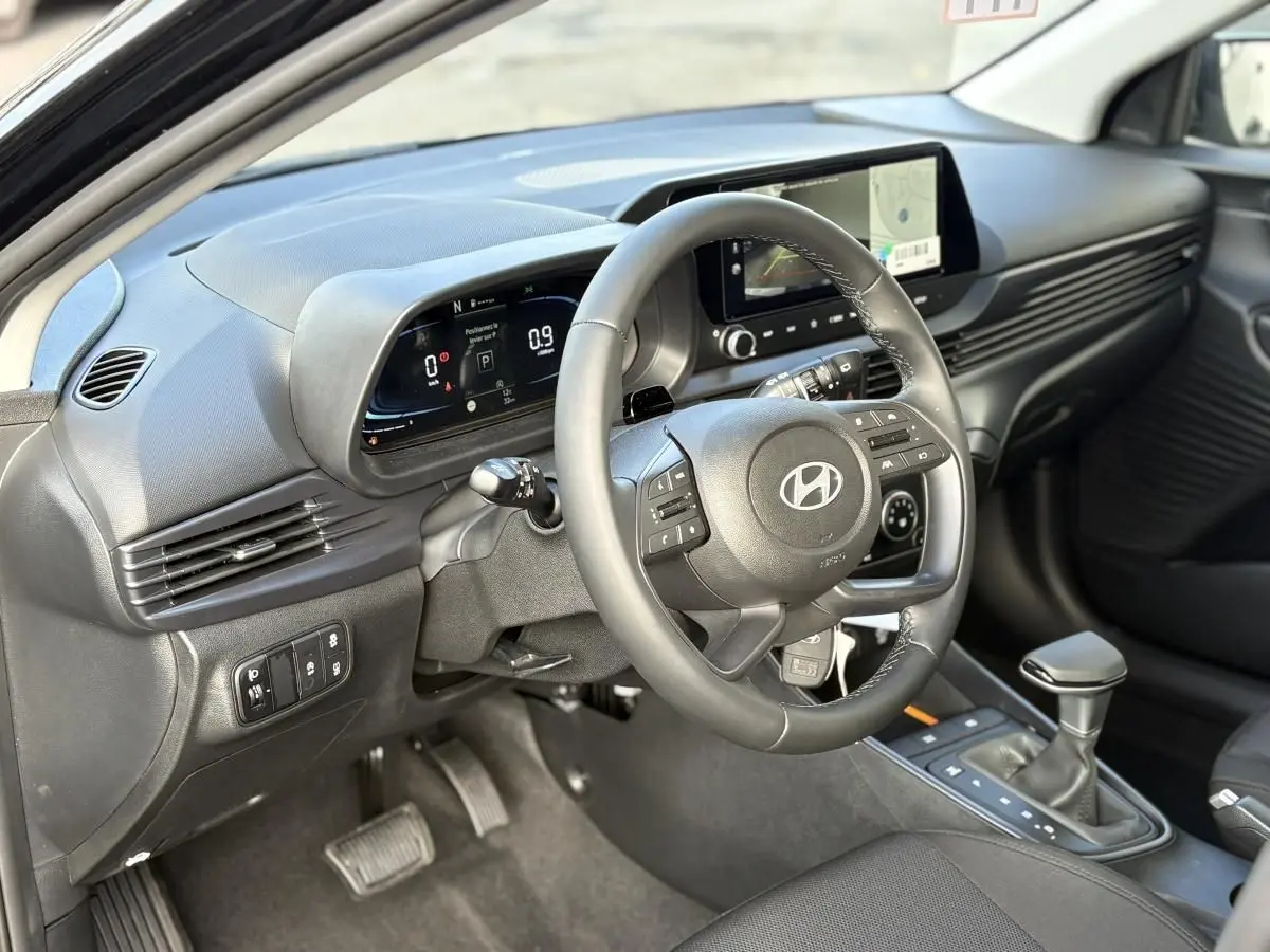 Vue intérieure côté conducteur de la Hyundai i20 2026 noir métal, avec tableau de bord digital et volant multifonction.