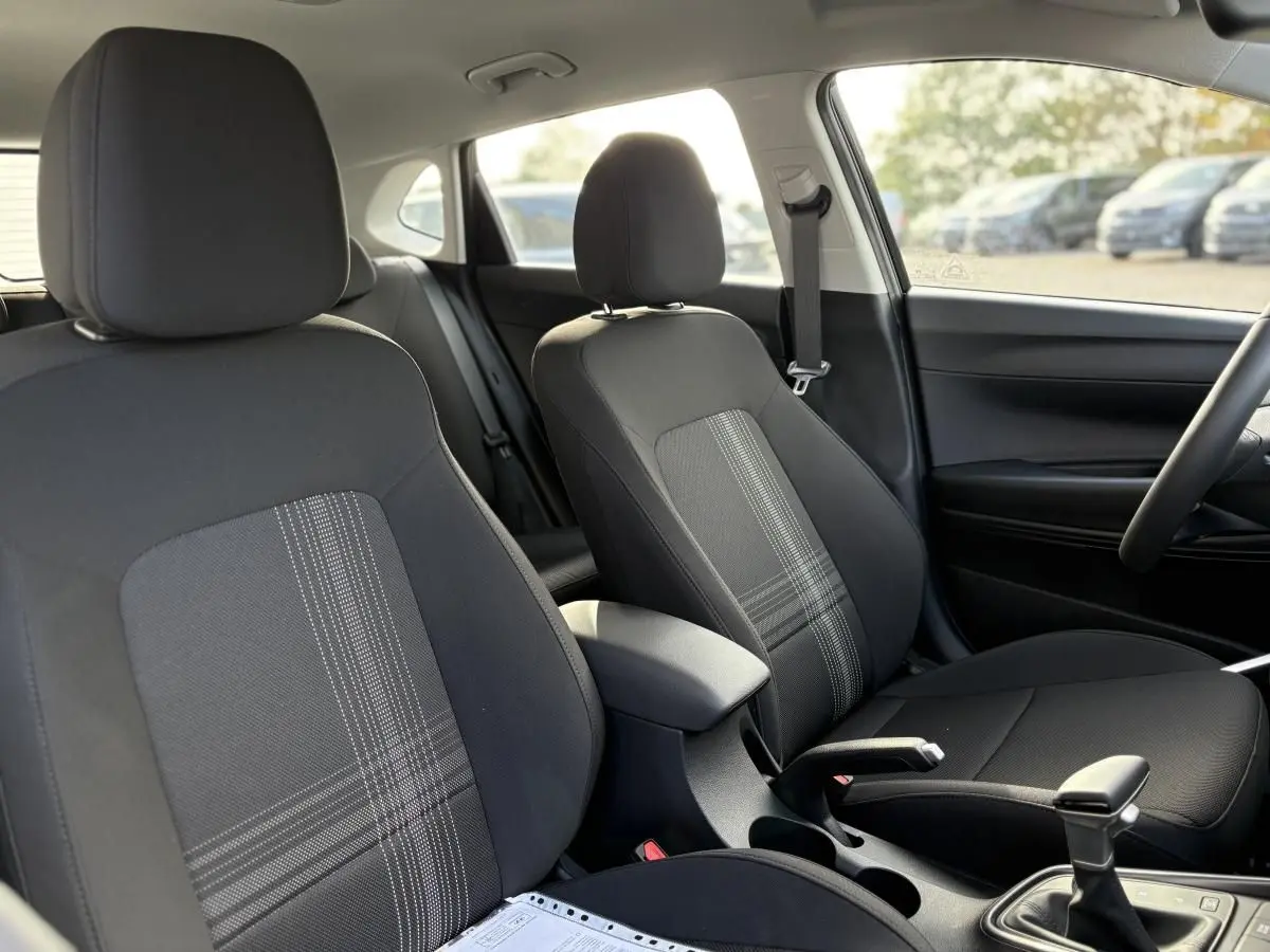 Vue intérieure côté droit de la Hyundai i20 2026 noire métal, montrant les sièges avant en tissu avec motifs gris.