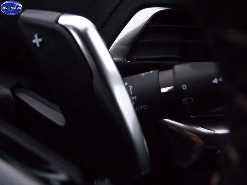 Gros plan sur la palette de changement de vitesse côté droit en aluminium dans l’habitacle sombre du Peugeot 3008 gris Artense.