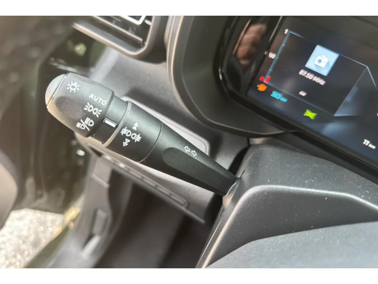 Gros plan sur la manette des feux et clignotants du Citroën Berlingo 2025, intérieur noir avec combiné numérique.