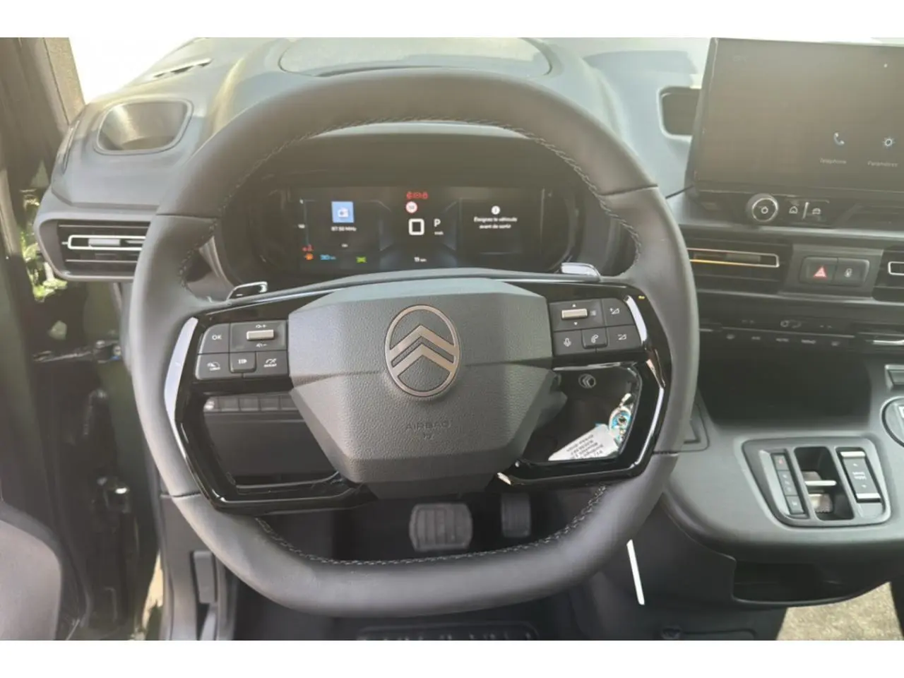 Vue rapprochée du volant multifonction noir et du tableau de bord numérique du Citroën Berlingo 2025.