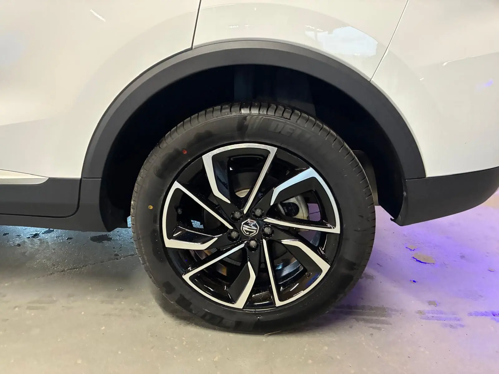 Gros plan sur la roue arrière droite du MG ZS blanc 2022, avec jante alliage noire et argentée au design moderne.