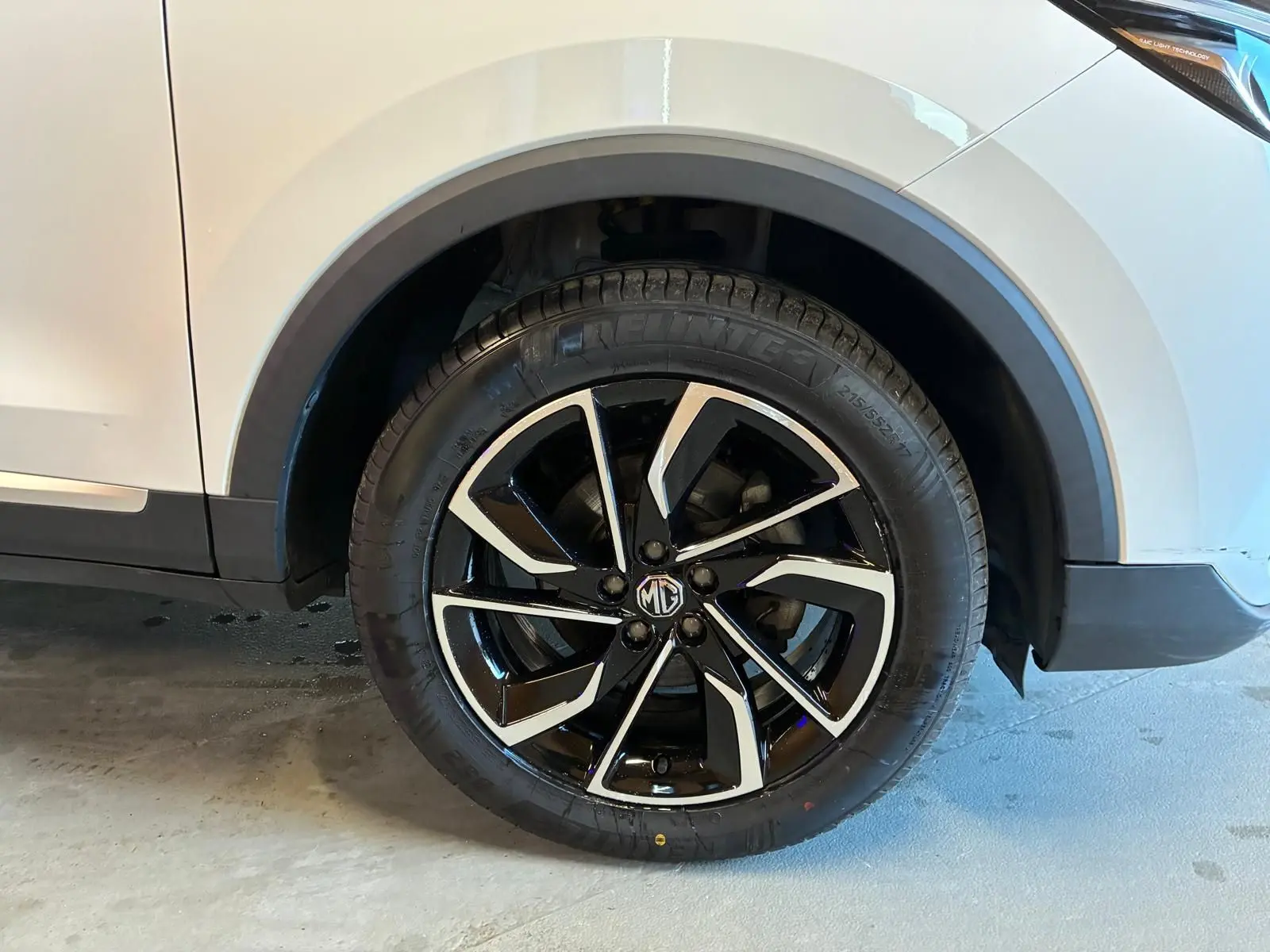 Gros plan sur la roue avant droite du MG ZS blanc 2022, mettant en valeur la jante noire et argentée au design moderne.