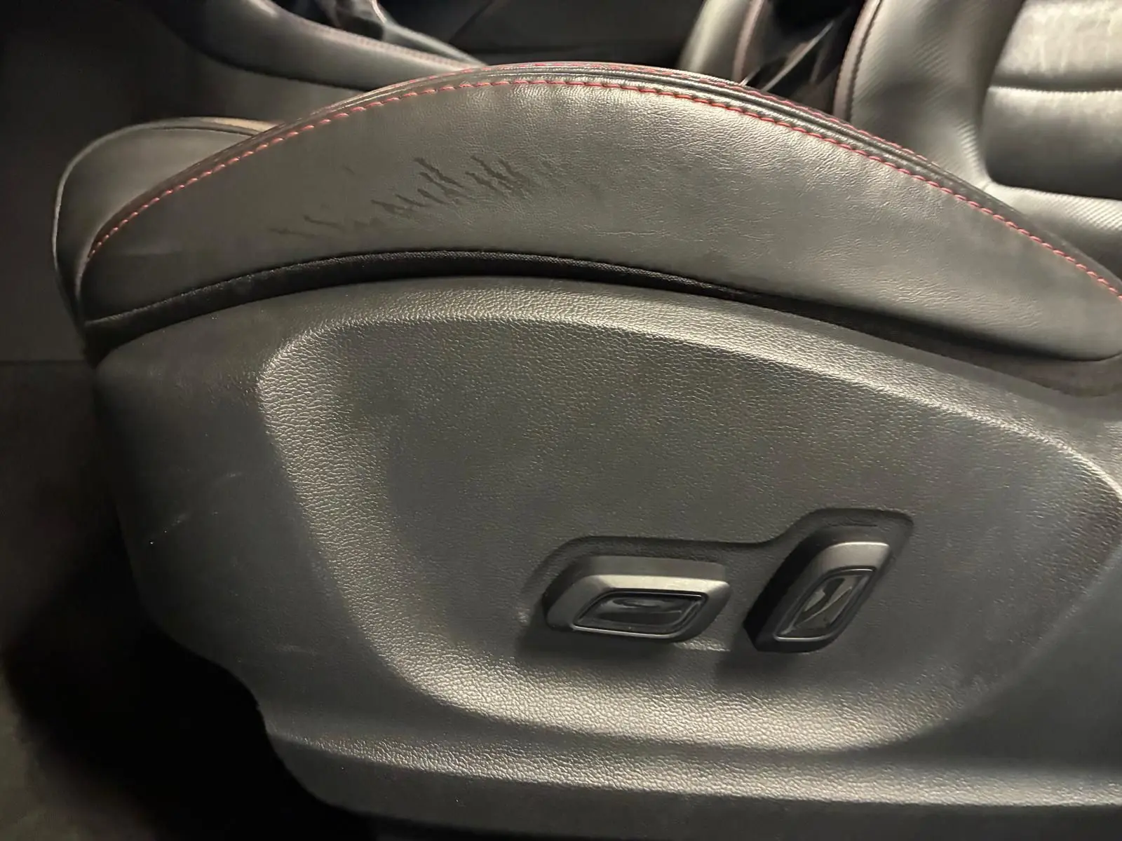 Gros plan sur les commandes de réglage électrique du siège avant en cuir noir avec surpiqûres rouges du MG ZS blanc.