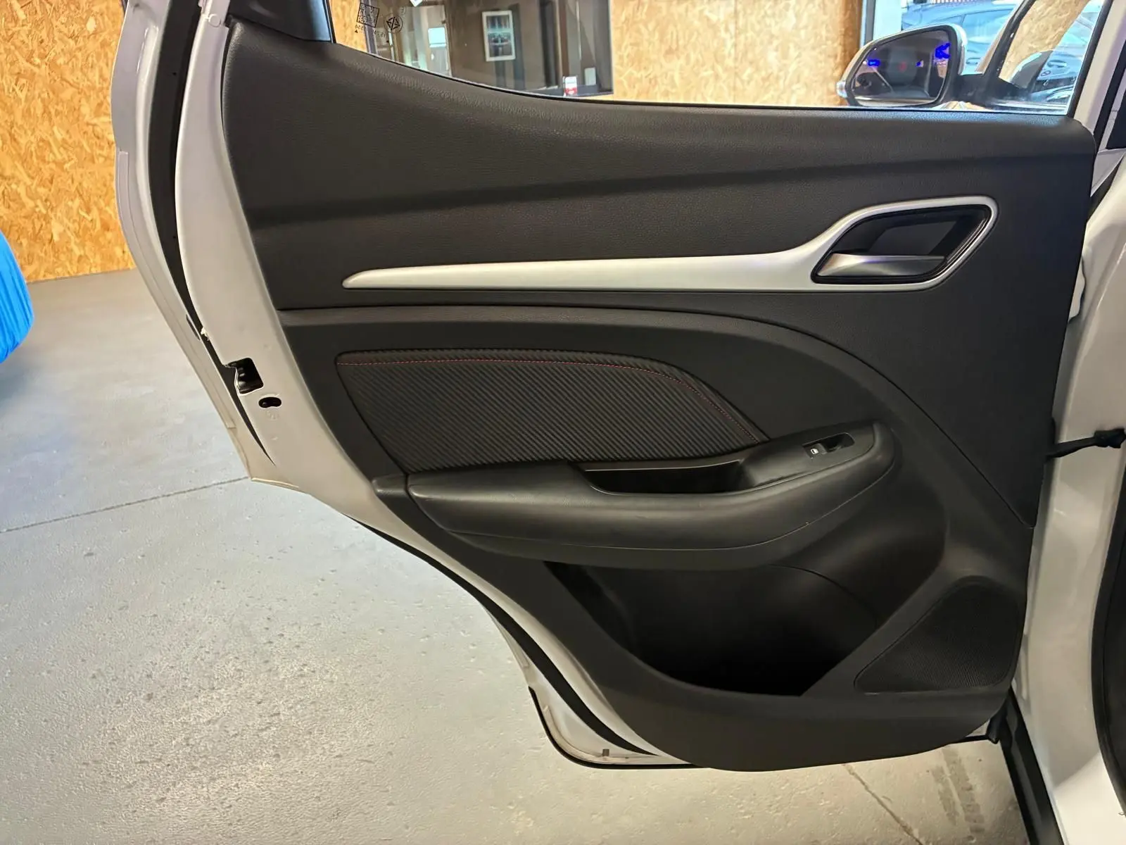 Vue intérieure de la porte arrière droite blanche du MG ZS 2022, avec garniture noire et poignée argentée.