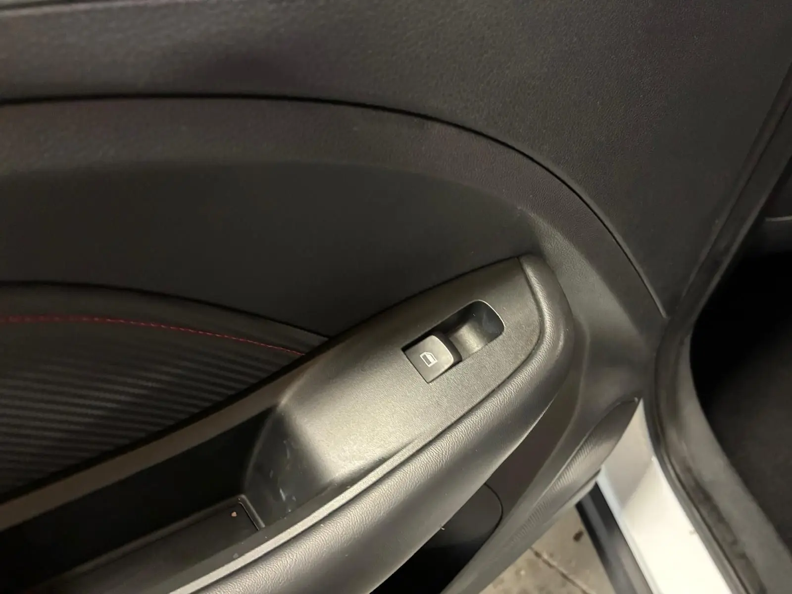 Gros plan sur le bouton de commande de la vitre électrique côté conducteur d’un MG ZS blanc, intérieur noir.