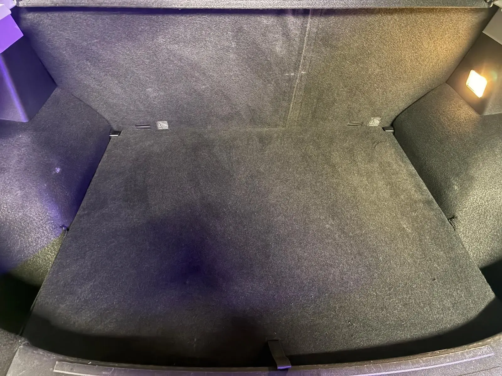 Vue intérieure du coffre spacieux et propre du MG ZS blanc, éclairé par une lampe intégrée sur le côté droit.