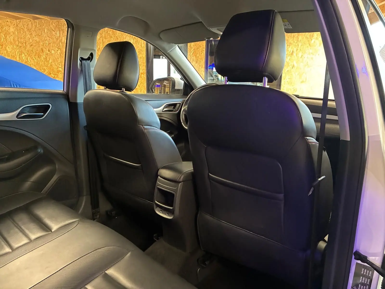 Vue intérieure arrière du MG ZS blanc 2022, montrant les sièges avant en cuir noir et la banquette arrière.