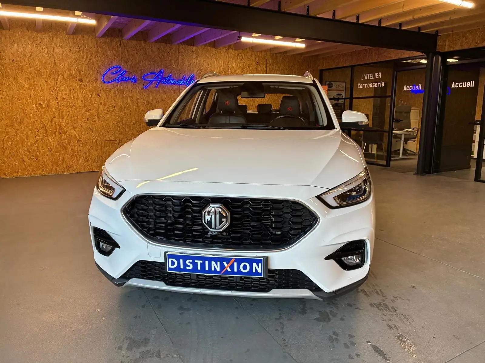 Vue avant d’un MG ZS blanc 2022 en showroom, avec calandre noire et logo MG bien visible.
