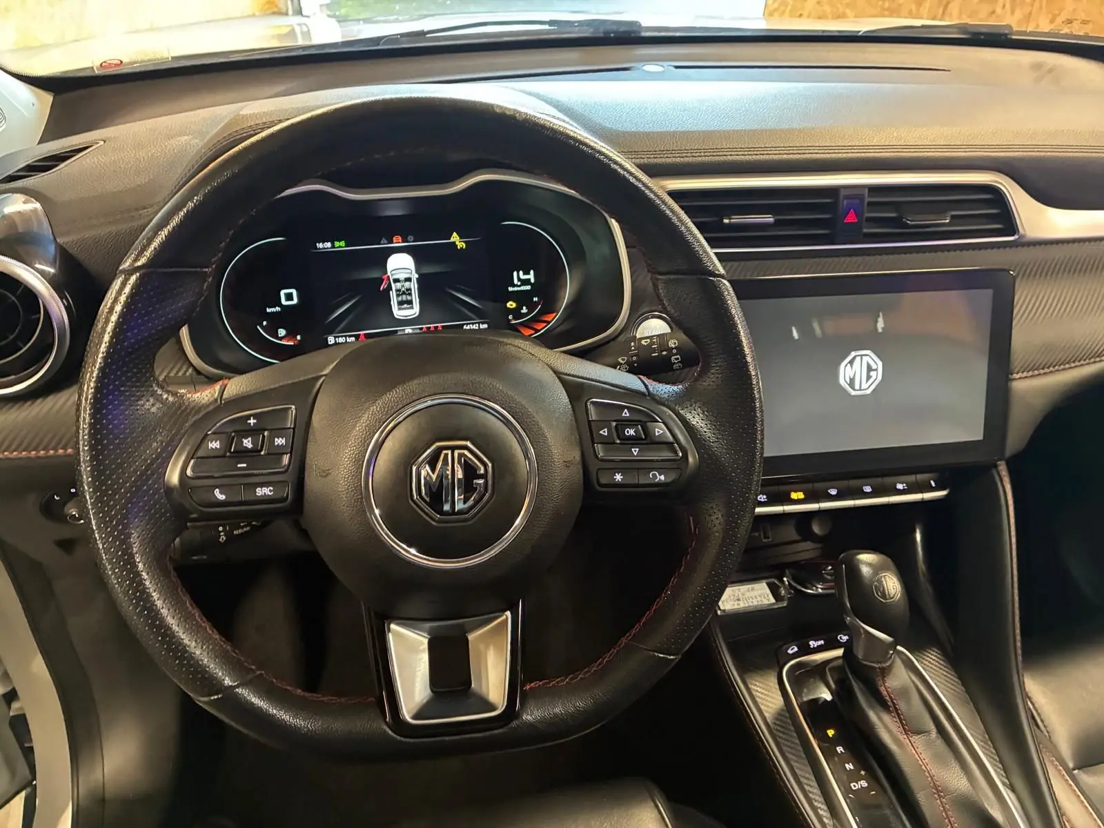 Vue intérieure centrée sur le volant noir perforé et l'écran tactile du tableau de bord du MG ZS blanc 2022.