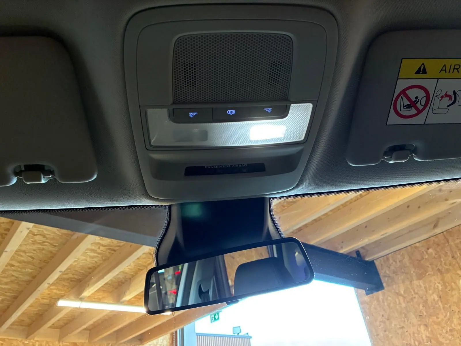 Vue intérieure du toit et du rétroviseur central d'un MG ZS blanc, avec éclairage de plafonnier et panneau de commande au plafond visible.