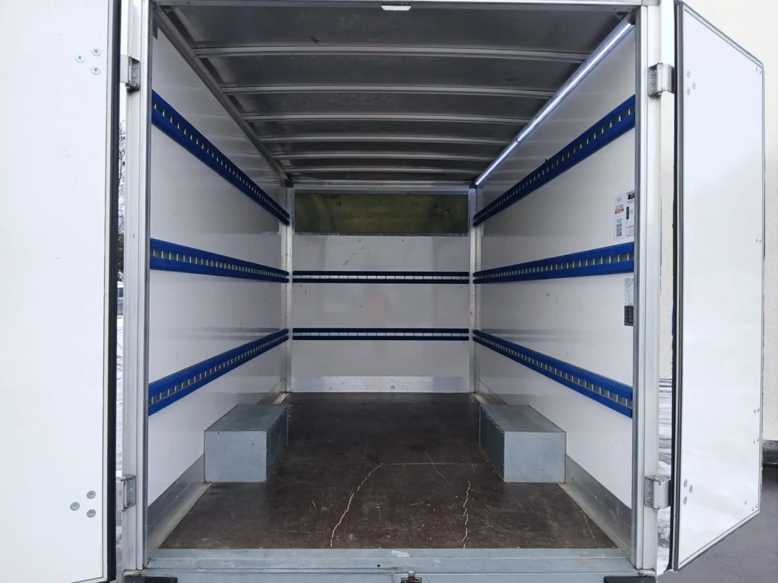 Vue intérieure arrière du Renault Master blanc 2023 avec caisse de chargement vide et rails bleus sur les parois.