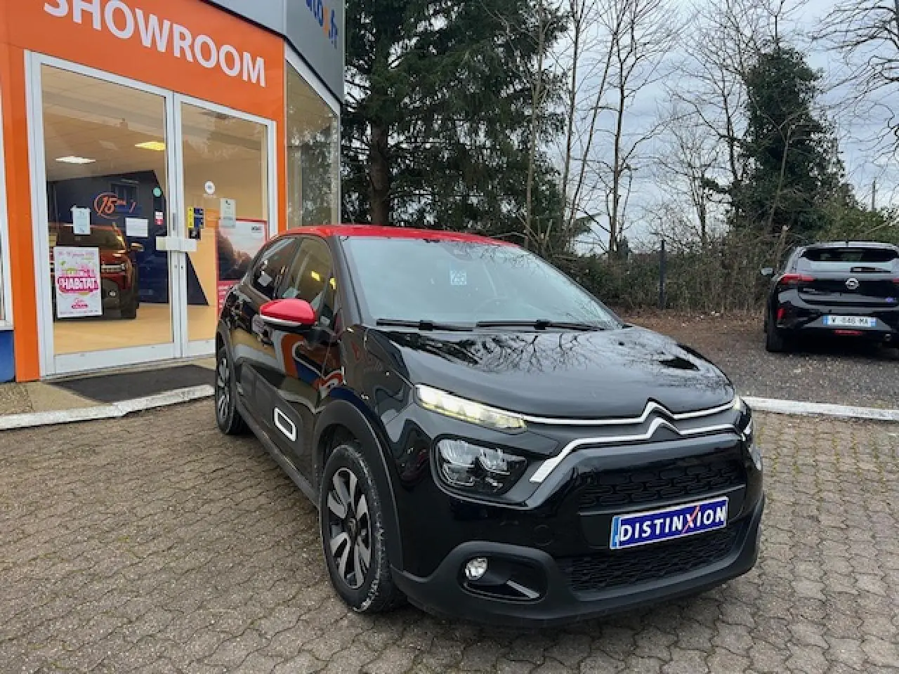 Citroën C3 Shine 2023 vue 3/4 avant droit, noir avec toit et rétroviseurs rouges, jantes alliage diamantées.