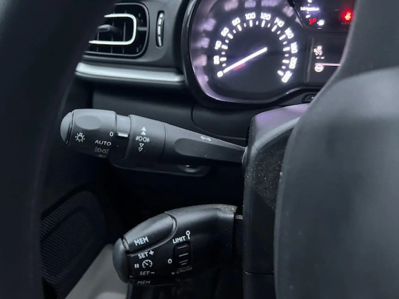 Détail intérieur du tableau de bord de Citroën C3 Shine 2023, montrant les commandes au volant et le compteur lumineux.