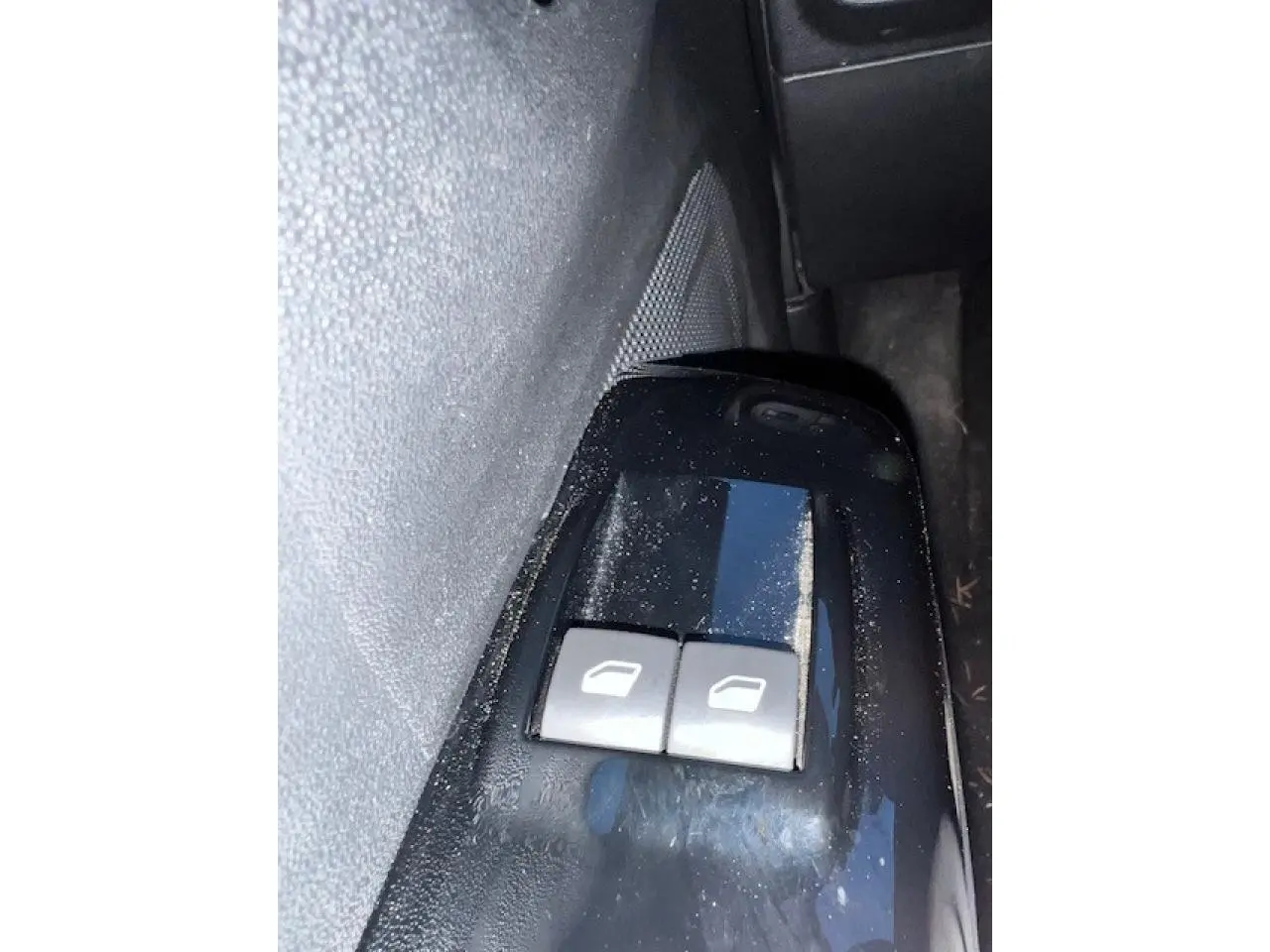 Gros plan sur les commandes des vitres électriques côté conducteur de la Citroën C3 Shine 2023 noir toit rouge.