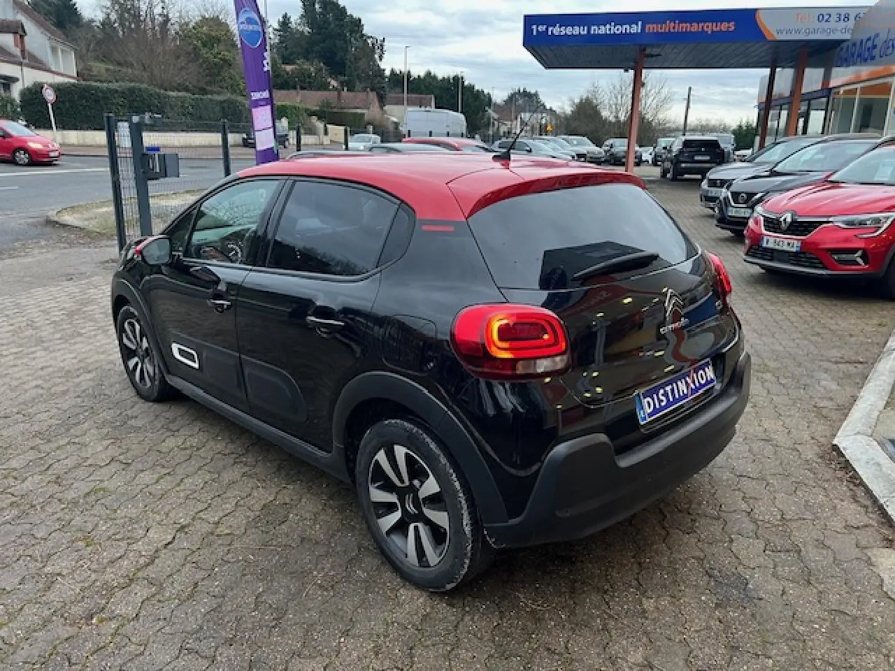 Vue 3/4 arrière droite d'une Citroën C3 Shine 2023 noire avec toit rouge et jantes alliage diamantées.