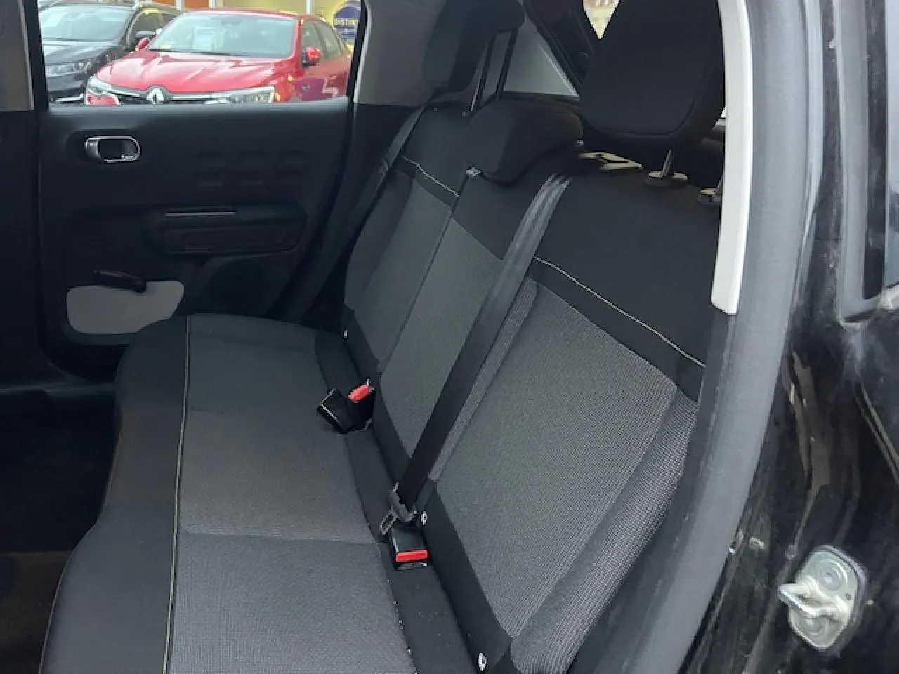 Vue intérieure côté droit sur la banquette arrière noire et grise d'une Citroën C3 Shine 2023 toit rouge visible partiellement.
