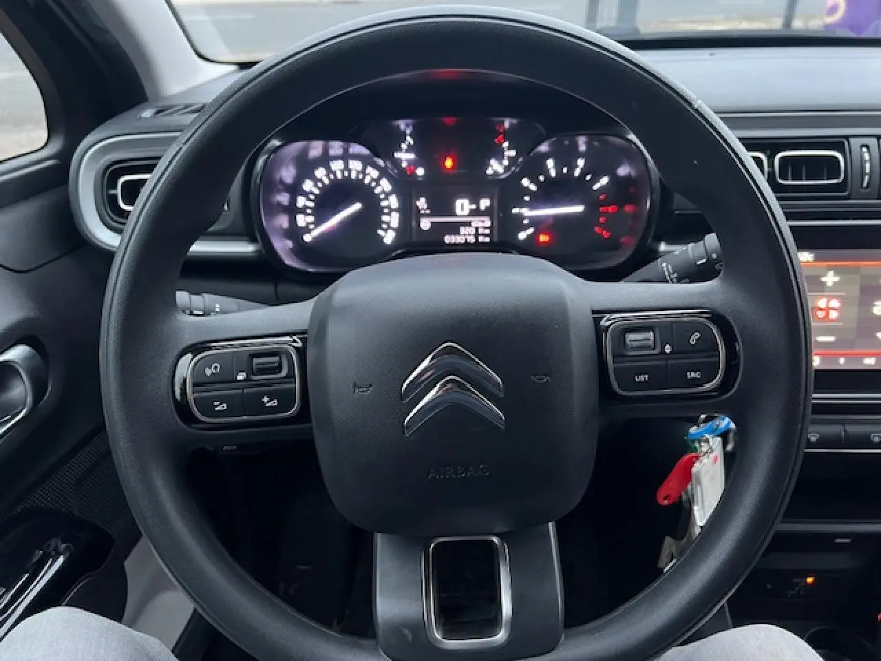 Vue centrée sur le volant noir de la Citroën C3 Shine 2023, avec commandes intégrées et tableau de bord éclairé.
