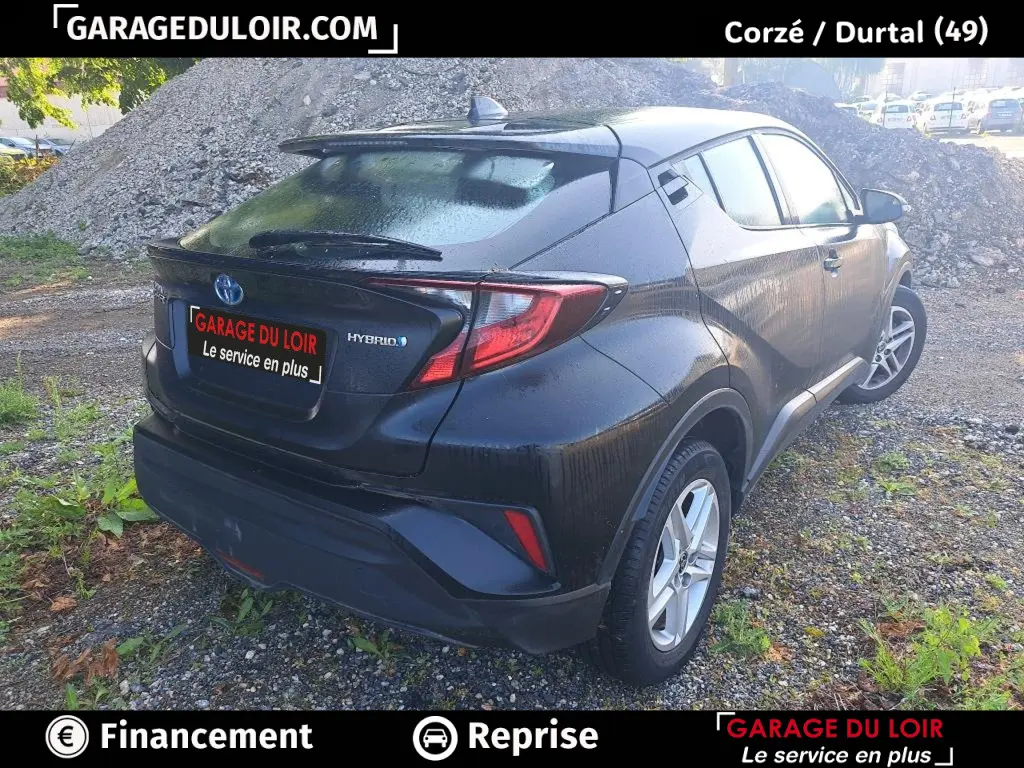Vue 3/4 arrière droite d'un Toyota C-HR hybride noir avec feux arrière LED et toit avec aileron.