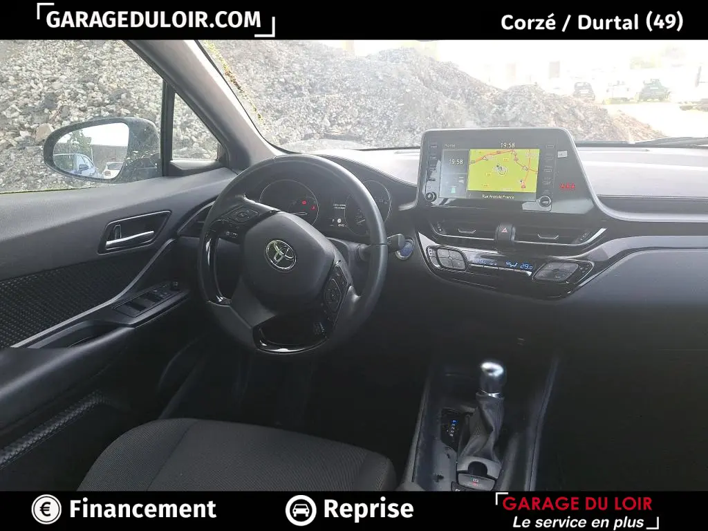 Vue intérieure côté conducteur du tableau de bord noir du Toyota C-HR 1.8 Hybride avec écran tactile et volant multifonctions.