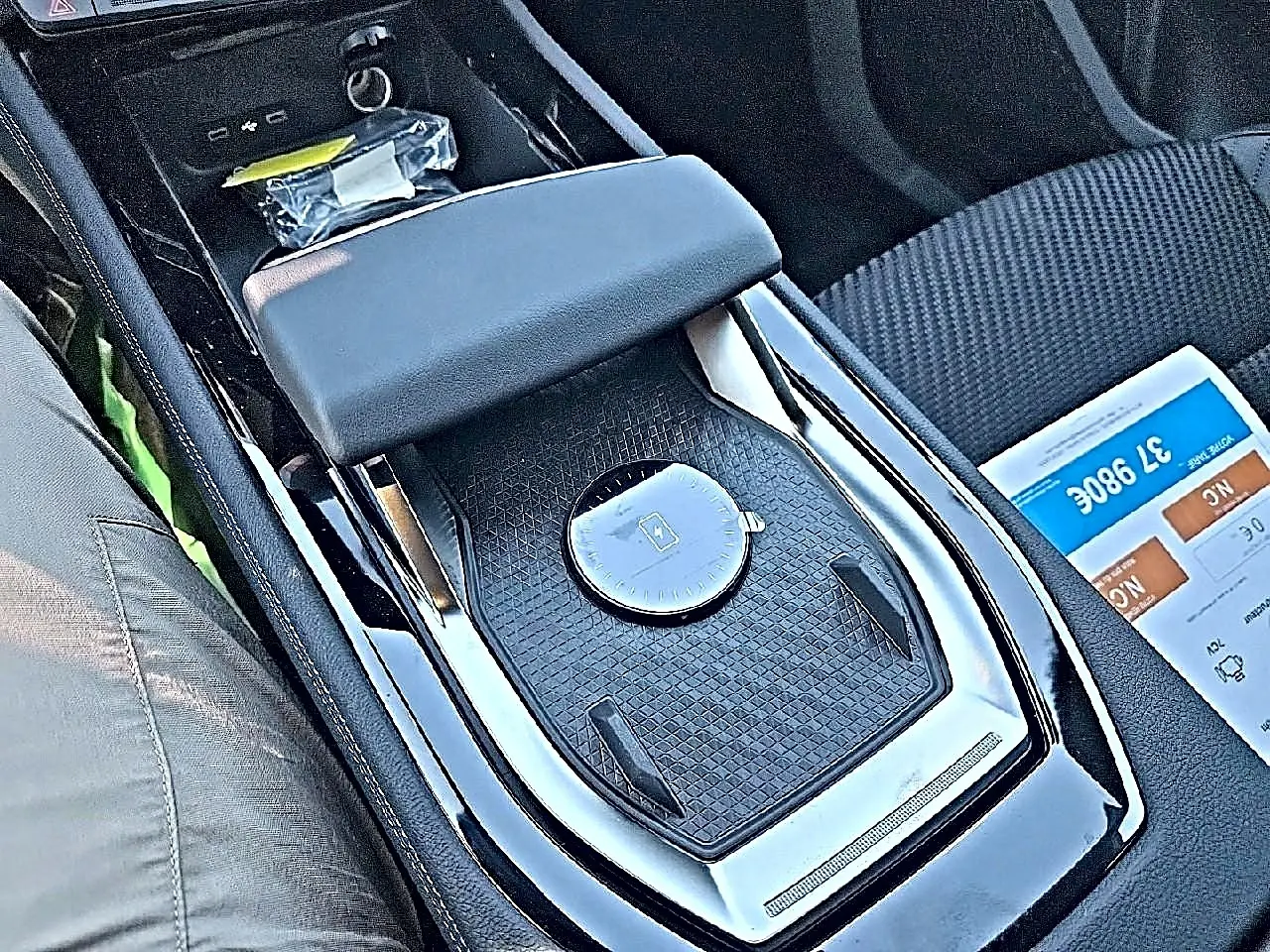 Gros plan sur l'accoudoir central et la console noire brillante du Renault Austral 2026, intérieur tissu carbone.