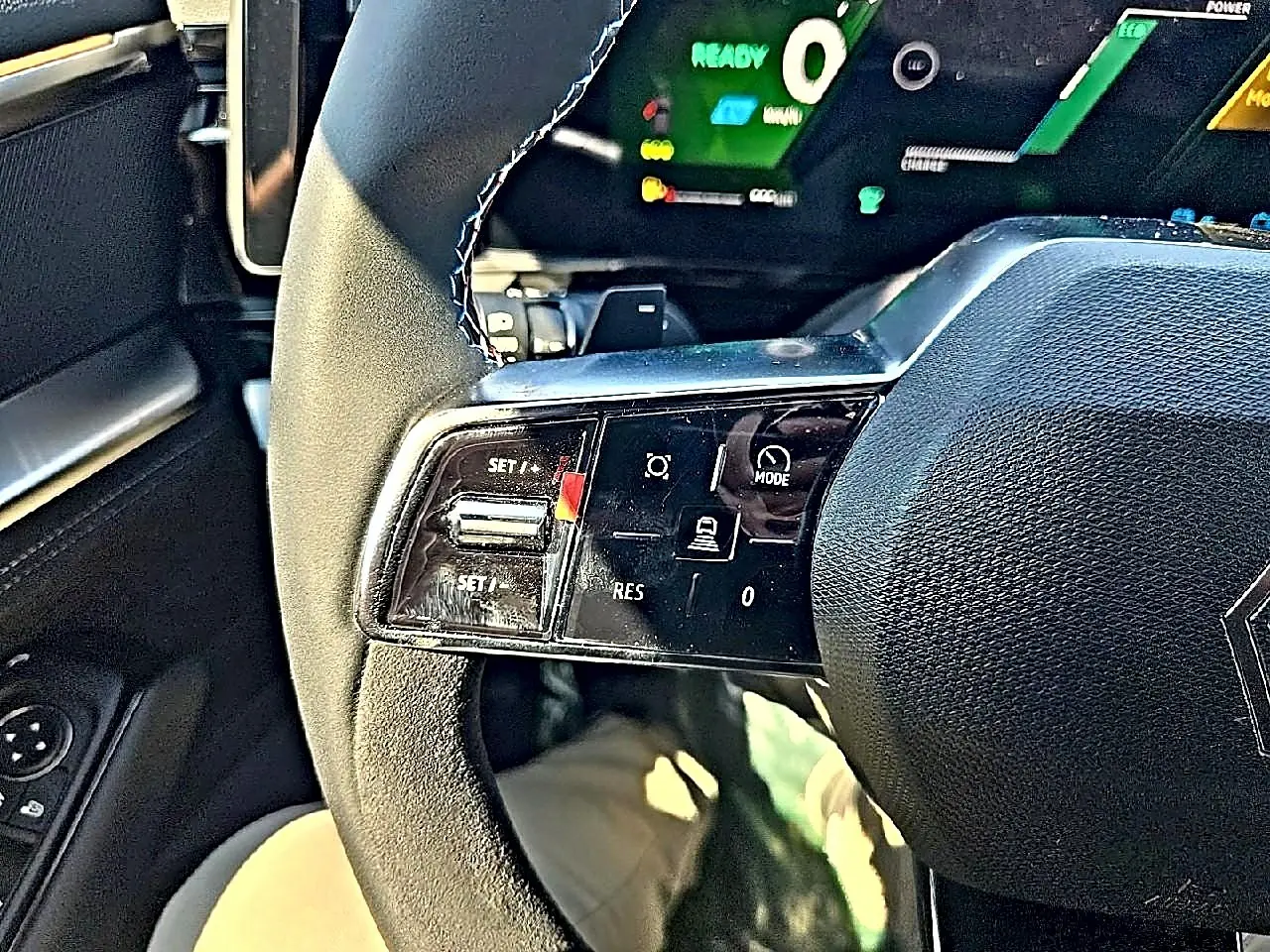 Gros plan sur le volant noir multifonction du Renault Austral blanc nacré, avec commandes de régulateur de vitesse visibles.