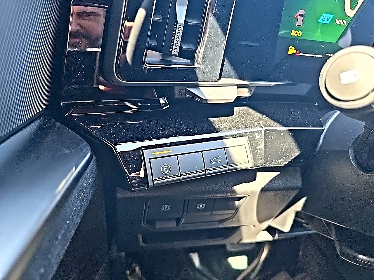 Gros plan sur la console centrale noire brillante du Renault Austral blanc nacré, avec commandes de verrouillage et hayon.