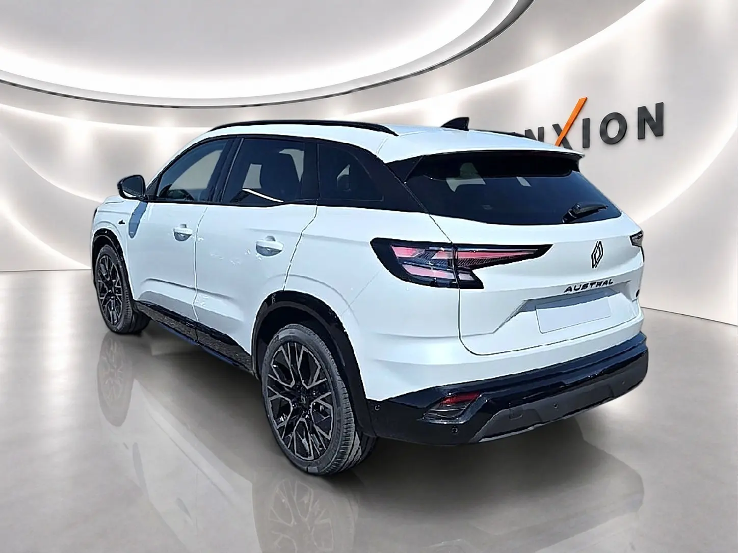 Renault Austral blanc nacré en 3/4 arrière droit, avec jantes noires et toit noir contrasté dans un showroom.
