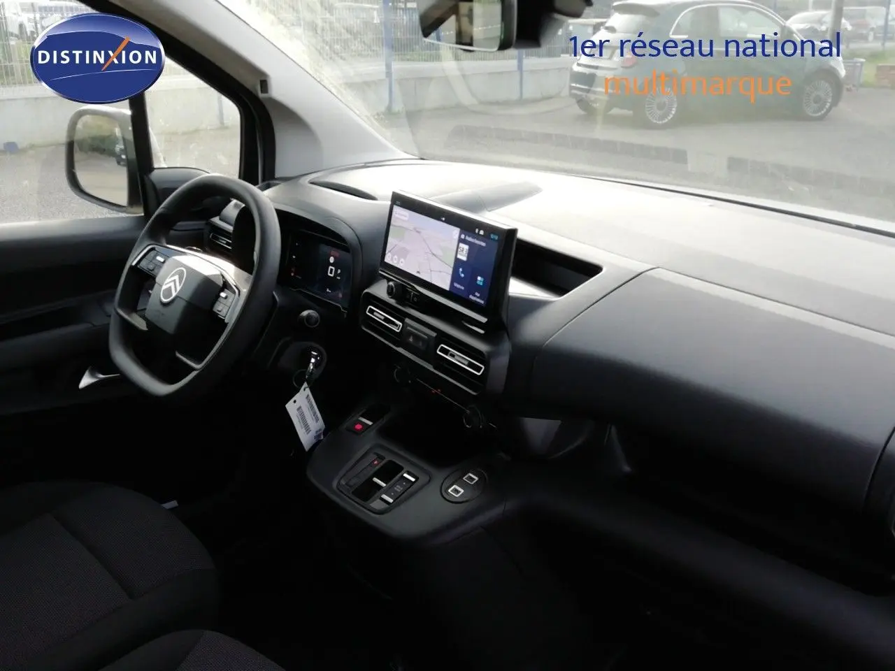 Intérieur du Citroën Berlingo XL 2026 vu côté conducteur, tableau de bord noir avec écran tactile central allumé.