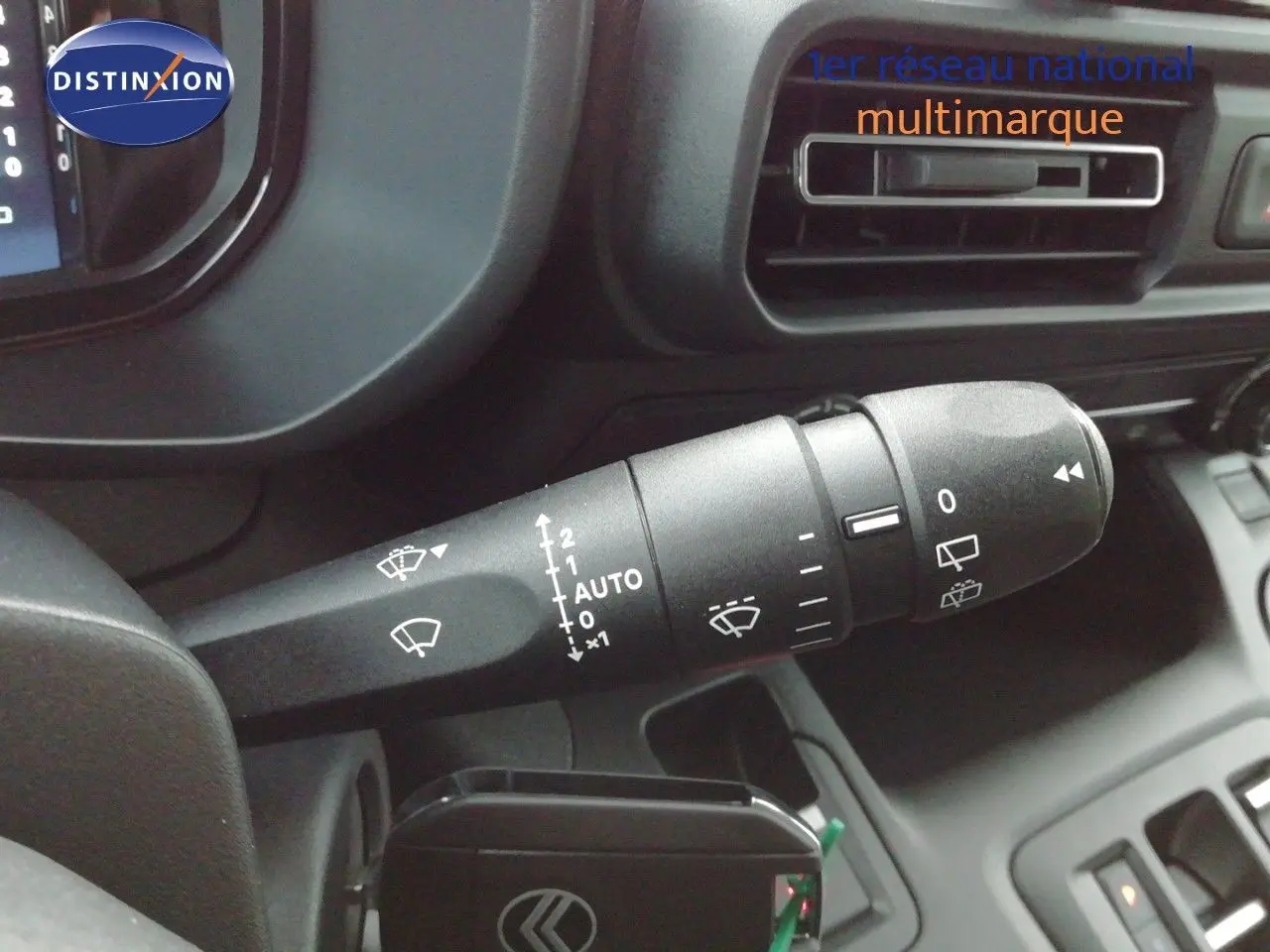 Gros plan sur la commande d’essuie-glace noire dans l’habitacle du Citroën Berlingo XL blanc, avec tableau de bord partiel visible.