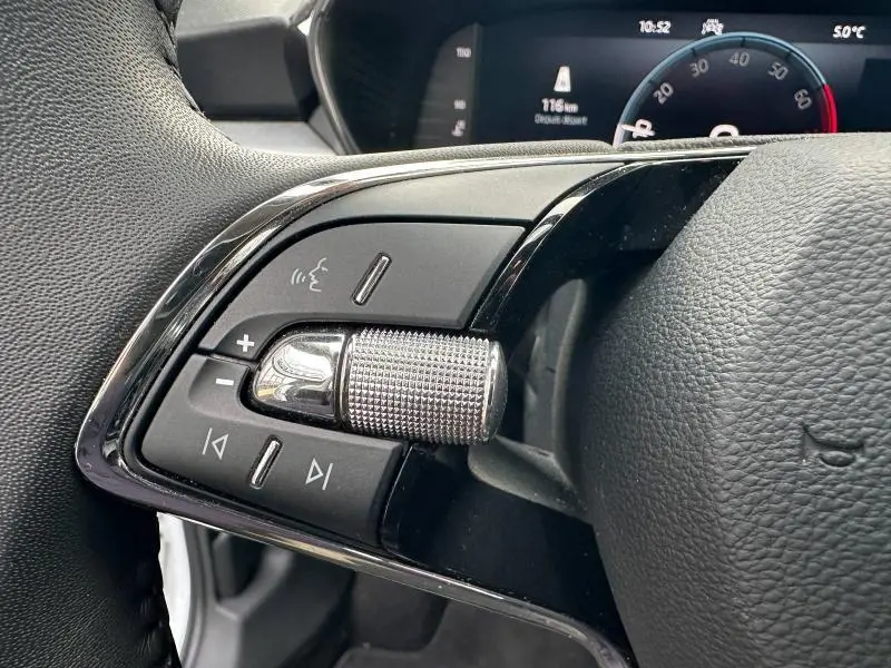 Gros plan sur les commandes audio et vocales sur le côté gauche du volant cuir d'une Skoda Fabia bleue 2024.