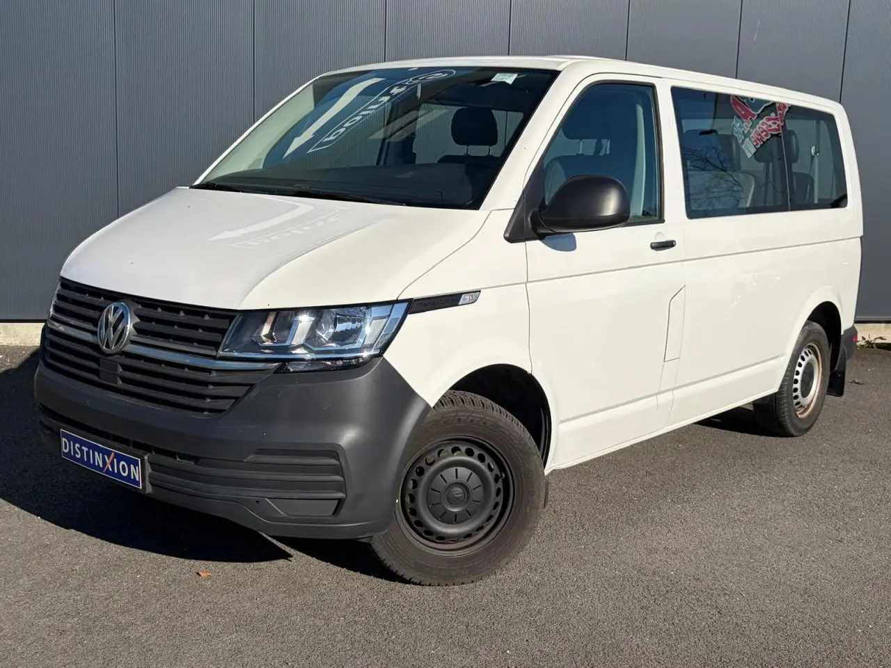 Vue 3/4 avant droit d’un Volkswagen Transporter T6 Minibus blanc avec pare-chocs noir et jantes acier.