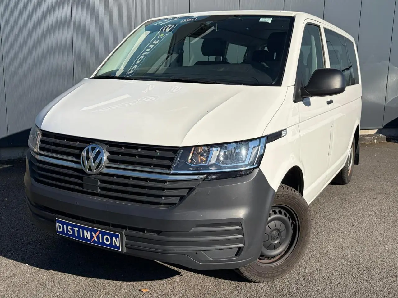 Vue 3/4 avant droit d'un Volkswagen Transporter T6 Minibus blanc avec pare-chocs noir et jantes acier.