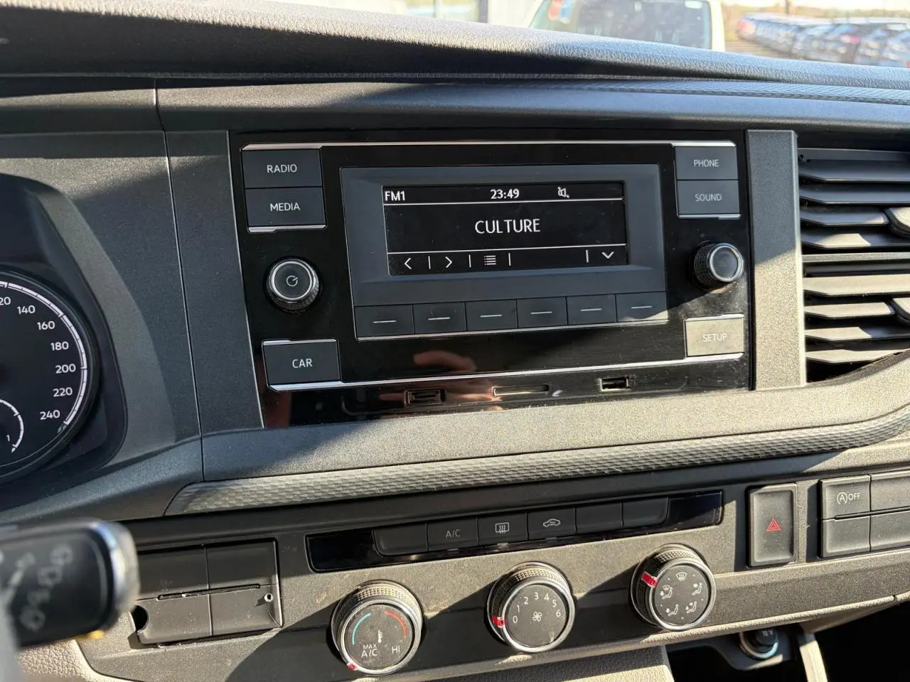 Gros plan sur la console centrale du Volkswagen Transporter T6 blanc, avec écran radio et commandes de climatisation visibles.