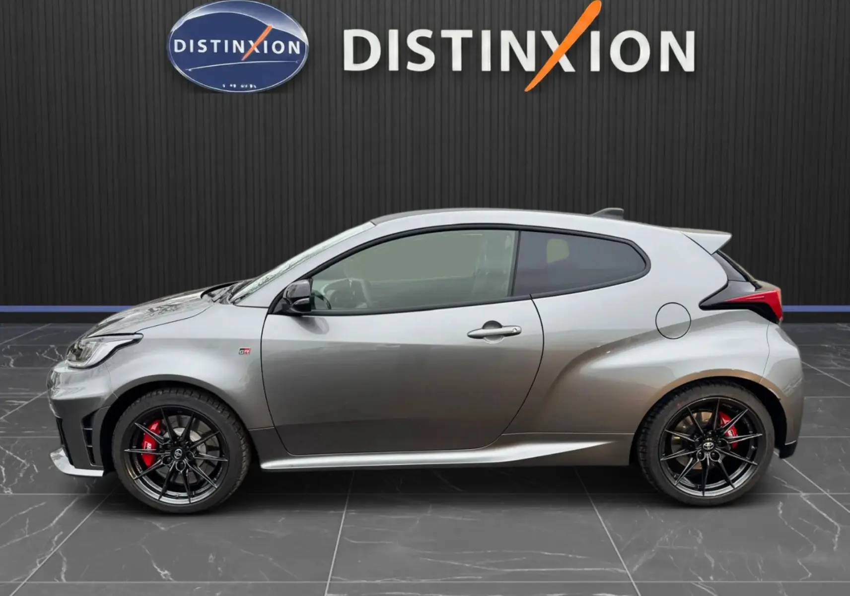 Profil droit de la Toyota Yaris GR gris platine avec jantes noires BBS et étriers de frein rouges visibles.