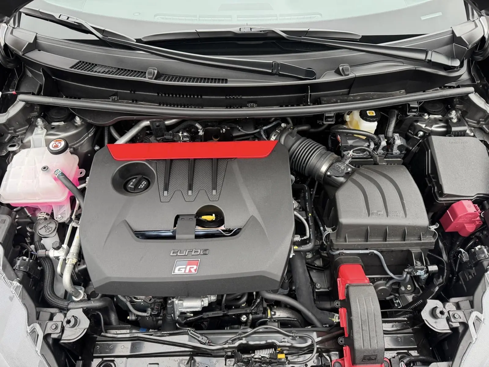 Vue plongeante sur le moteur turbo gris et noir avec logo GR rouge de la Toyota Yaris GR Pack Techno.