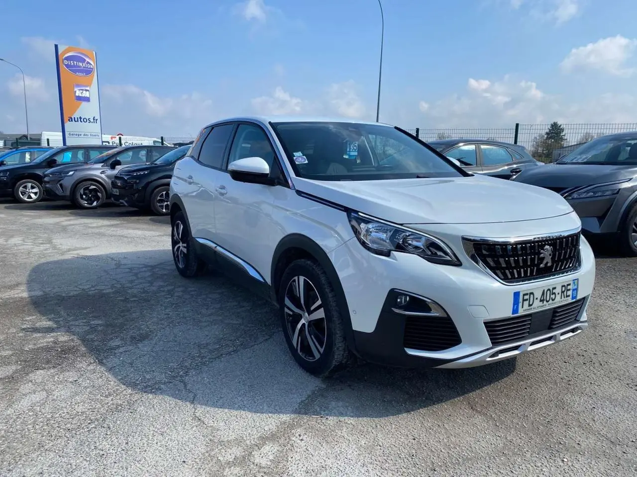 Peugeot 3008 blanc vue 3/4 avant droit, avec jantes alliage et calandre noire distinctive, sur parking extérieur.